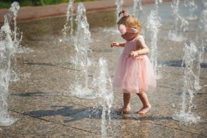 little girl plays with water in fountain