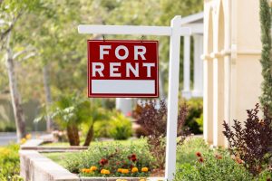 Red For Rent Real Estate Sign in Front House.