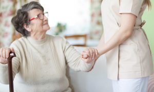 Older woman in chair getting help from nurse