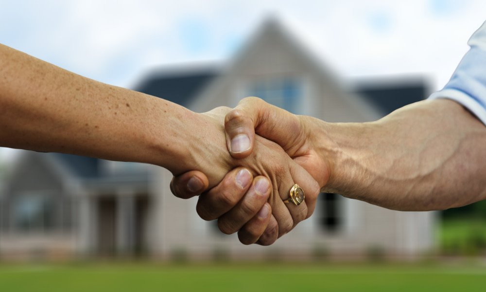 people shaking hands in front of house