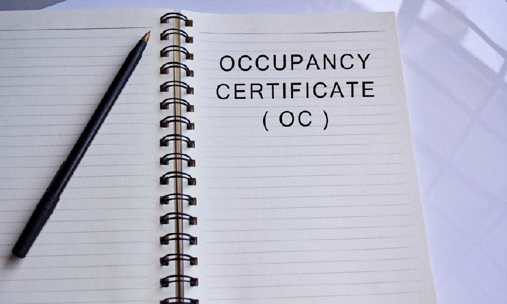 White notebook paper with black ink pen and words occupancy certificate (OC) in bold typeface, signifying a certificate of occupancy in D.C.