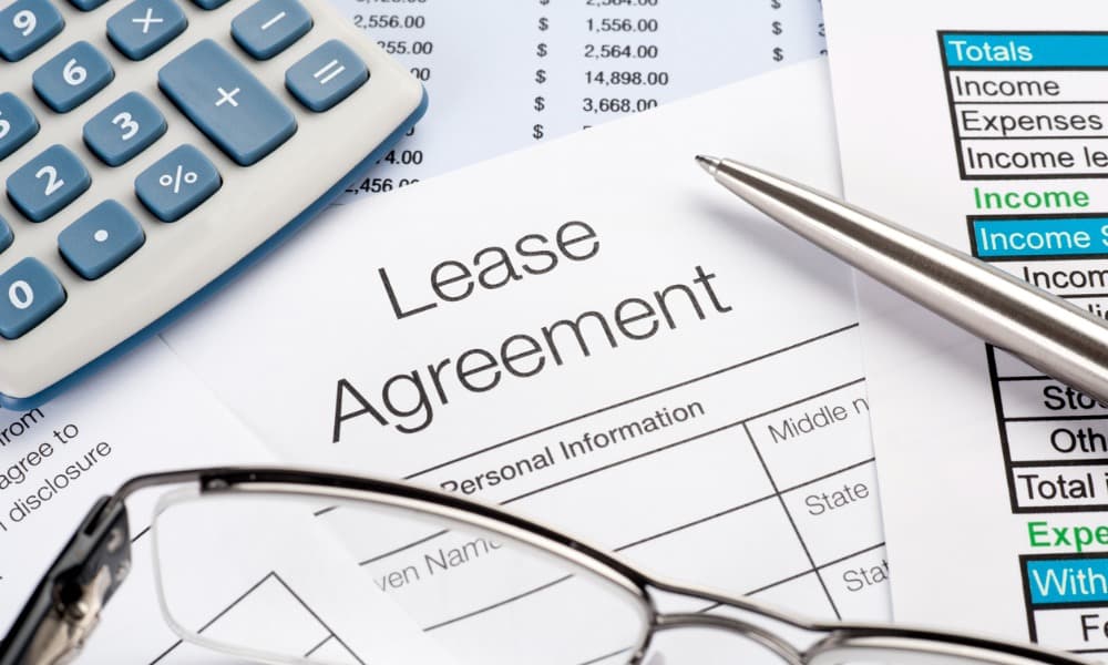 close-up of a commercial lease agreement with a pen, calculator, and glasses on the table