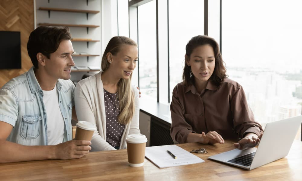 Landlord reviews good tenant qualities on a paper application and laptop with two potential renters