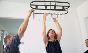 Two people hanging a light fixture to get ready to take real estate listing photos.