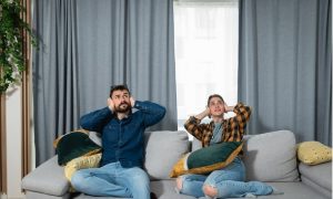 A couple sitting on a couch during a breach of the covenant of quiet enjoyment in their rental apartment