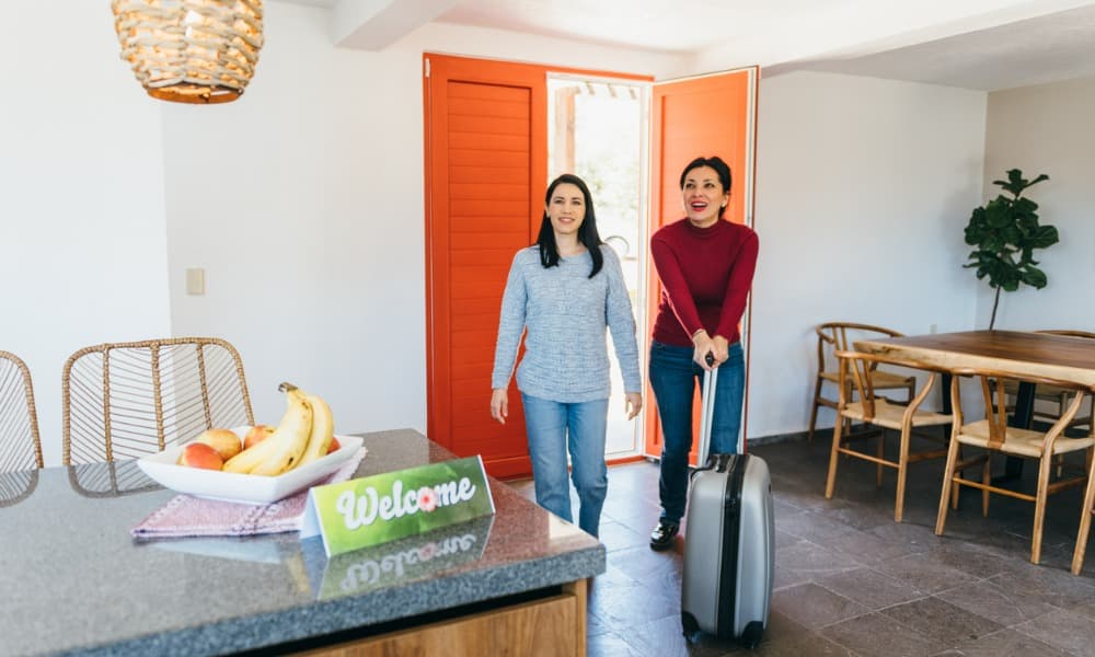 Two women in a short-term rental asking, “How much can you make on Airbnb?”