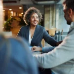 Happy real estate agent discussing terms with potential home buyers.