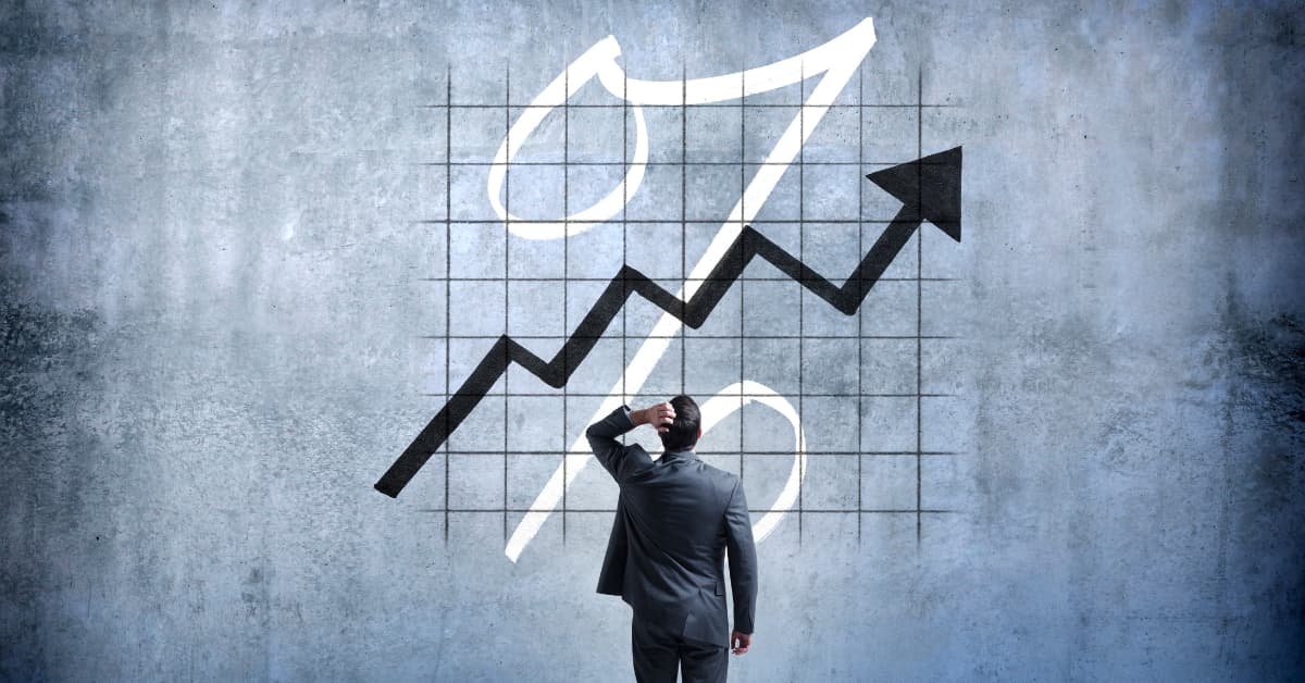 Businessman looking at a rising line graph and percentage symbol, representing increasing cap rates in real estate investing