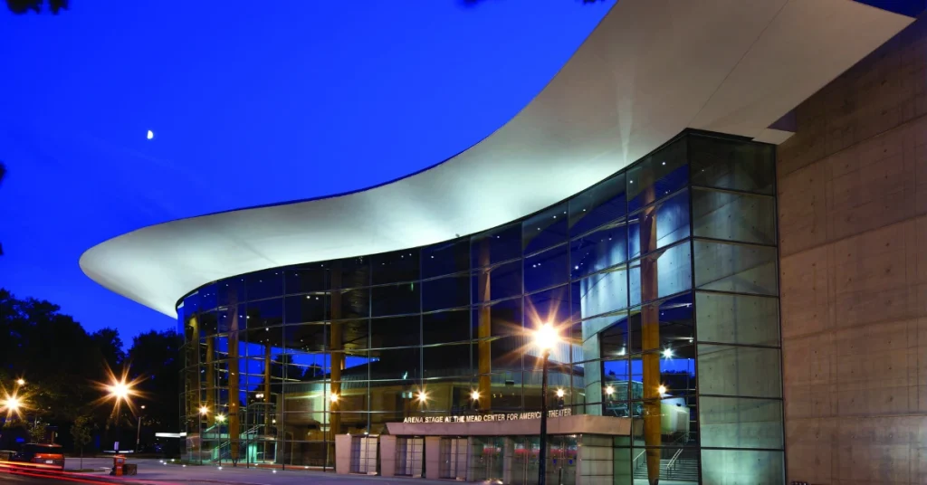 Night view of the Arena Stage at the Mead Center, a theater in Washington, D.C., illuminated with bright lights.