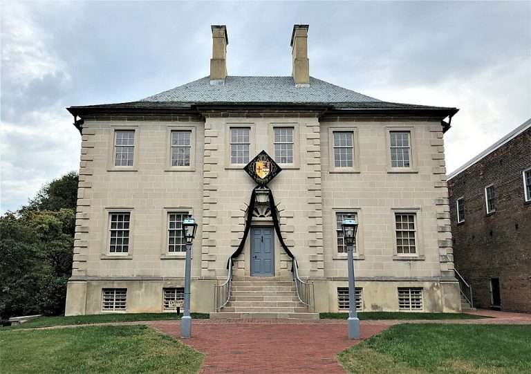 Carlyle House Historic Park - Georgian-style stone mansion with symmetrical windows, central blue door, grand staircase, and decorative coat of arms above entrance