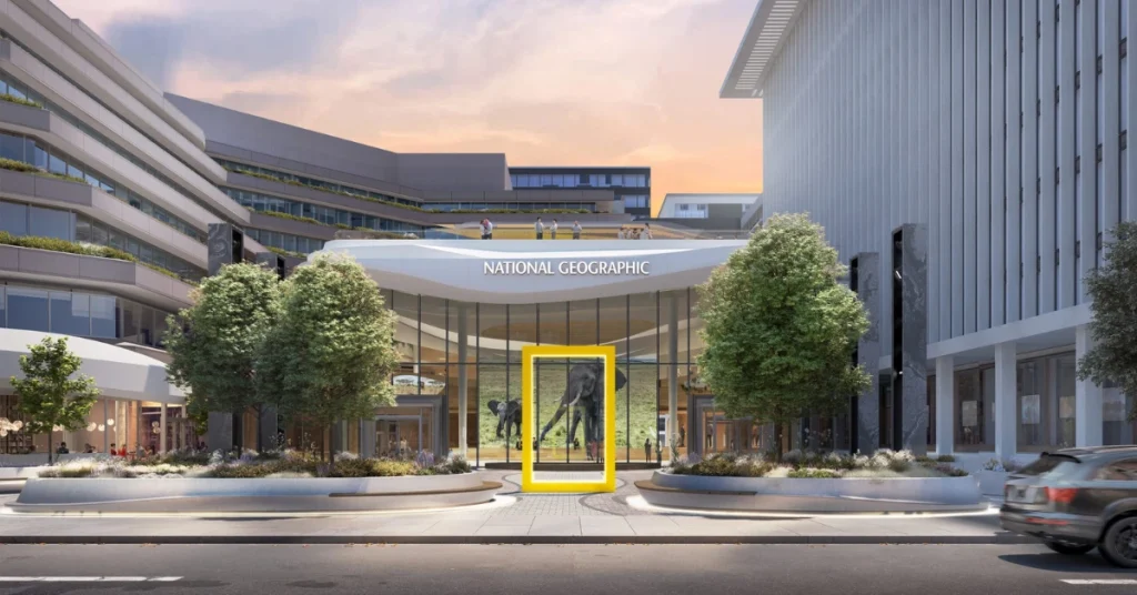 The National Geographic headquarters in Washington, DC, set to reopen in 2026 as the Museum of Exploration, featuring a sleek glass entrance, iconic yellow frame, and exhibit preview with elephant imagery.