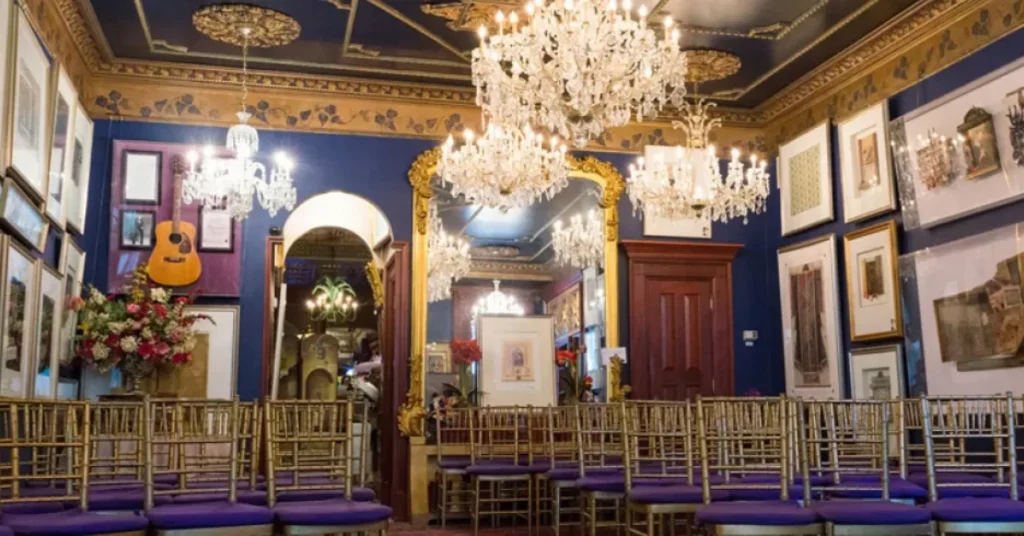 Ornate room inside the Mansion on O Street in Washington, DC, featuring crystal chandeliers, gold-framed mirrors, eclectic art, and rows of elegant chairs set up for an event.
