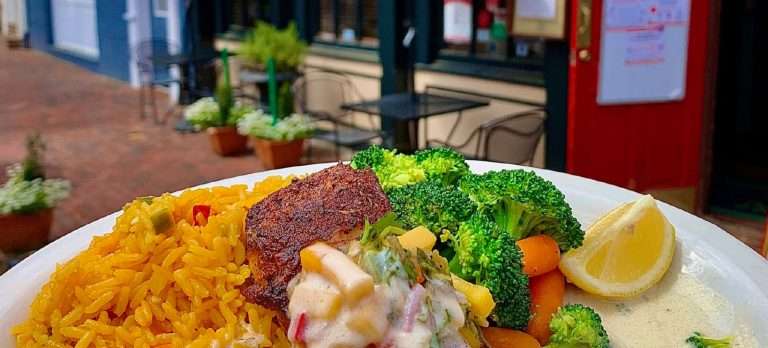 Murphy's Grand Irish Pub hearty plate featuring seasoned beef patty, yellow saffron rice, fresh broccoli and carrots, creamy sauce, and lemon wedge served at outdoor table
