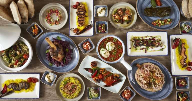 An overhead spread of vibrant Israeli dishes at Sababa in Cleveland Park, featuring grilled meats, fresh salads, hummus, shakshuka, breads, and colorful sides.