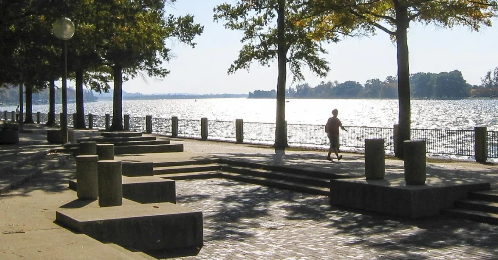 A scenic view of Southwest Waterfront Park with lush green trees, a walking path, and a calm river in the background.