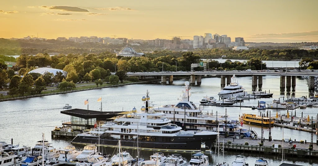 Luxury yachts docked at The Wharf Marina in Washington, D.C., bathed in the warm glow of a setting sun.