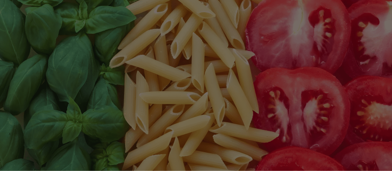 Fresh basil, uncooked penne pasta, and sliced tomatoes arranged side by side to resemble the colors of the Italian flag, symbolizing authentic Italian cuisine.