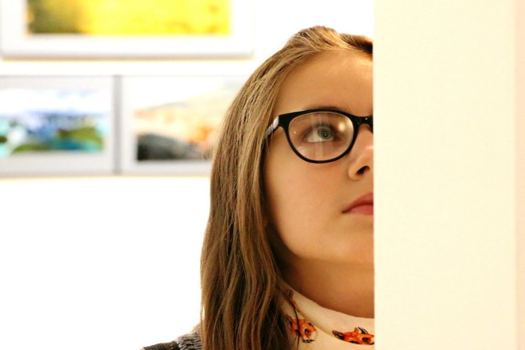 Girl with glasses looking at painting in museum