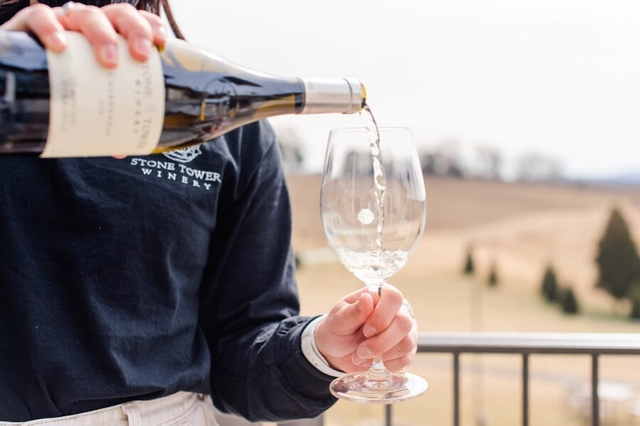 an employee pouring white wine from the bottle to a wine glass