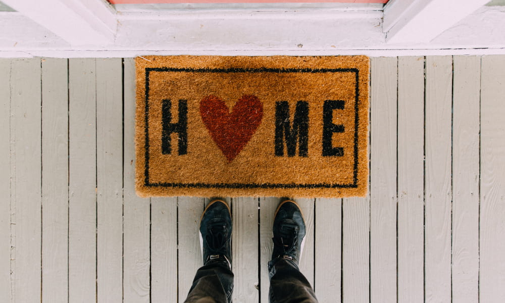 Welcome mat in front of house that says home