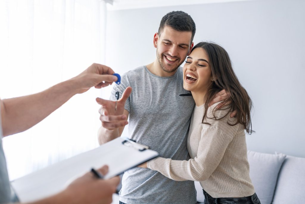 A happy couple taking possession of their house keys after purchasing it.