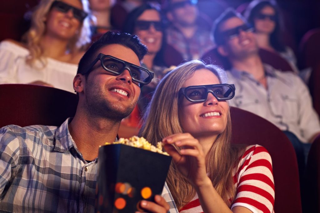 Couple watching movie at theater with glasses and popcorn