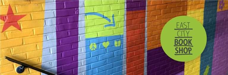 A brightly colored, striped brick wall mural with symbols of peace, love, and books, advertises East City Bookshop.(Copy)