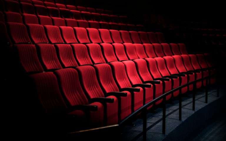 Rows of empty red seats in dim lighting at Roundhouse Theatre, creating a serene and theatrical atmosphere.