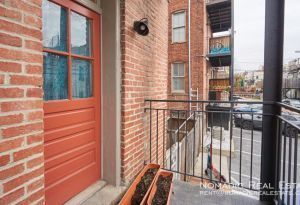 Brick balcony with red door, metal railing, and planter boxes.