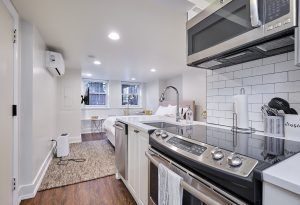 Modern studio apartment with kitchen, bed, and desk.